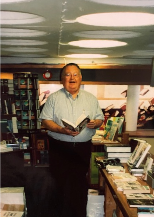 Man who is a professor is holding book at a bookstore.